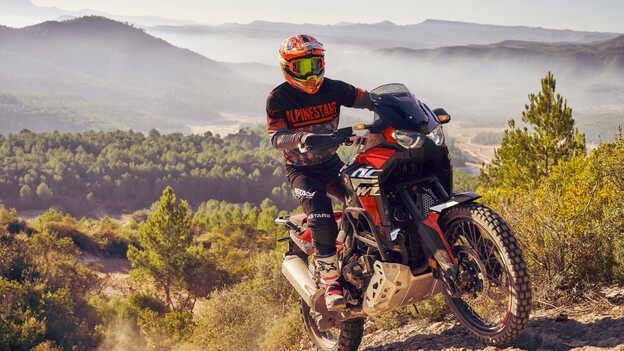 Front facing three quarter Honda Africa twin being ridden across rough terrain