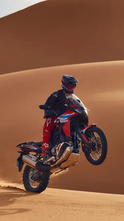 Model on CRF1100L Africa Twin bike in a desert location.