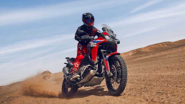 Model on CRF1100L Africa Twin bike in a desert location.