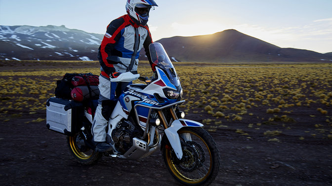 Front three-quarter facing Honda Africa Twin Adventure Sports with standing driver, mountain location.
