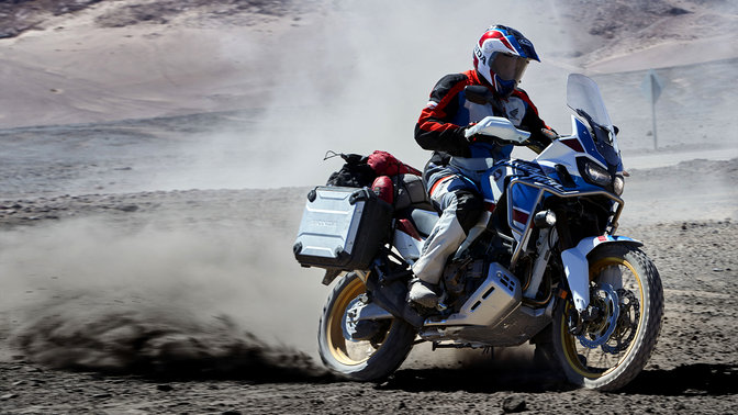Rider on Honda Africa Twin Adventure Sports motorcycle skidding off road.
