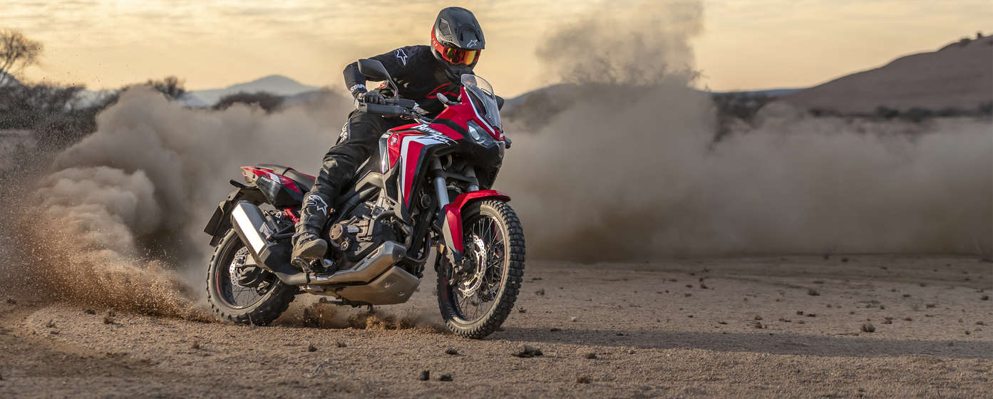 front angled view of a rider riding a honda africa twin adventure sports motorcycle on a dirt track
