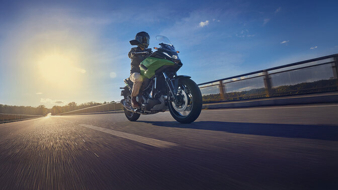 Model riding the NC750X motorcycle on a road.