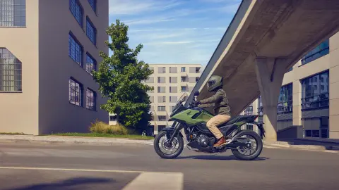 Side shot of a model riding the NC750X motorcycle in a city location.