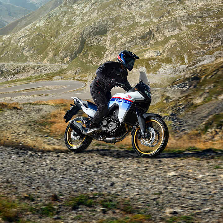 XL750 Transalp on gravel track in front of mountains.