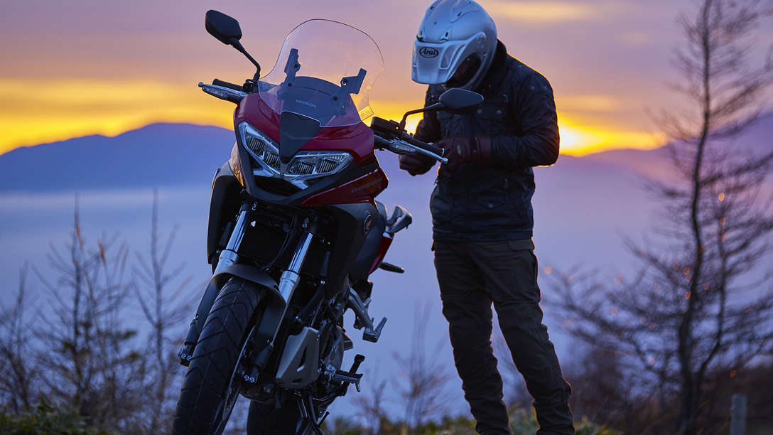 VFR800X parked in countryside landscape next to rider on foot