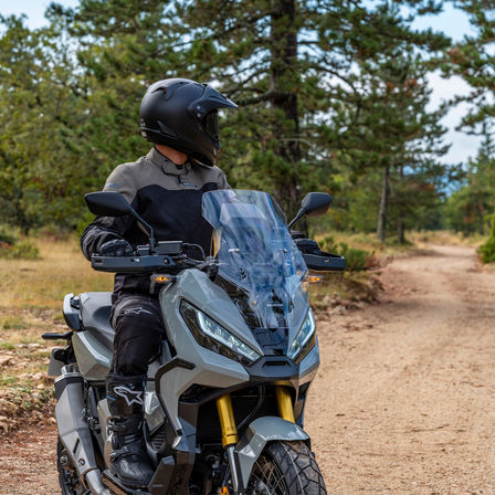 Honda X-ADV, 3-quarter front right side, rider standing on grey bike, forest track