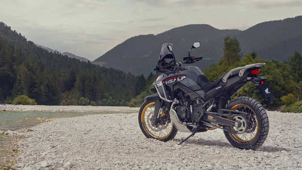 Rider holding the XL750 Transalp motorcycle in a mountain location.