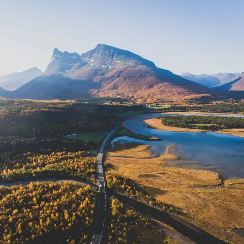 Classic norwegian scandinavian summer mountain landscape view with road, mountains and fjord with a blue sky, northern Norway, Finnmark County, shot from drone