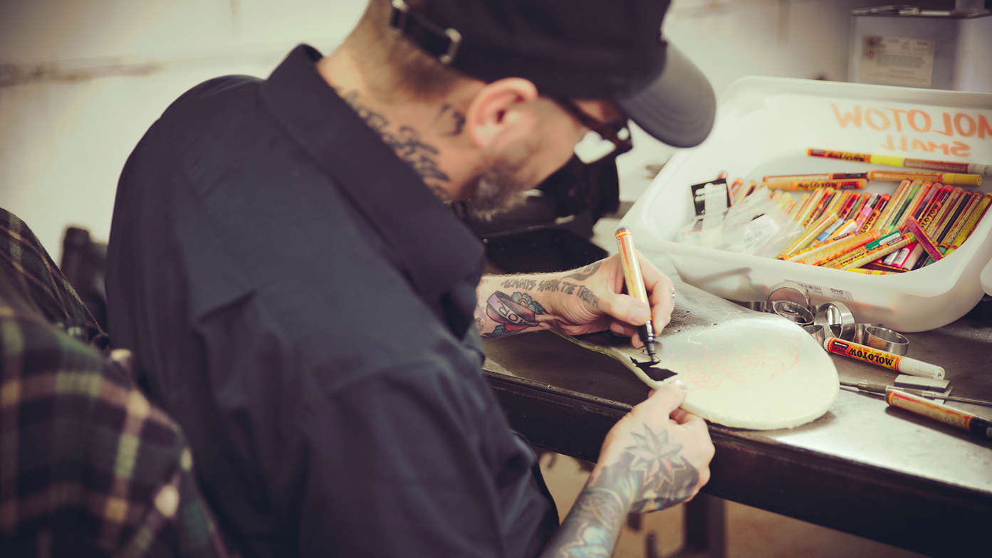 Dan Gold drawing on a skateboard.