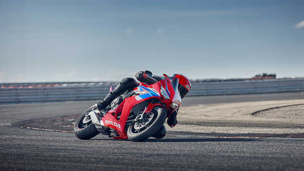 Model driving a motorbike on a road in a mountain location.