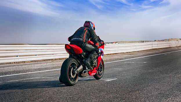 Model on a motorcycle driving in a race course location.