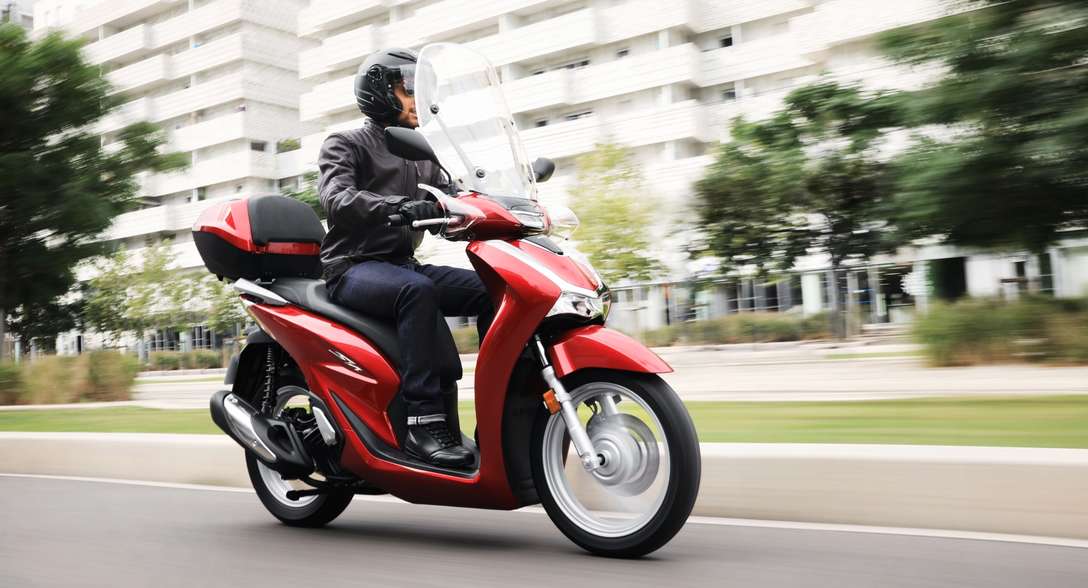 Honda SH125i, 3-quarter front right side, with rider, in the city