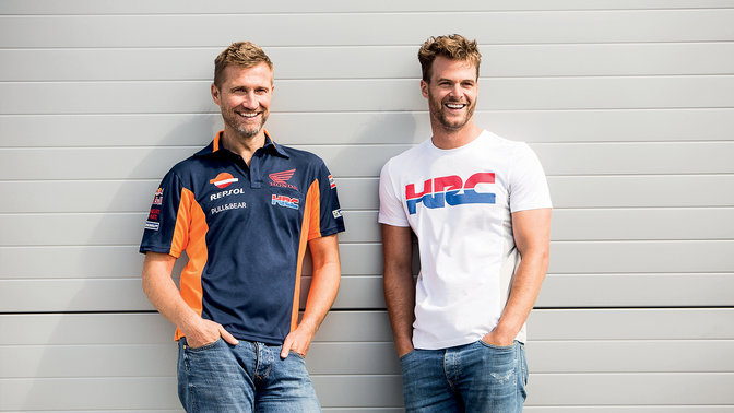 Two men smiling and laughing, they are wearing dark and white Honda shirts.