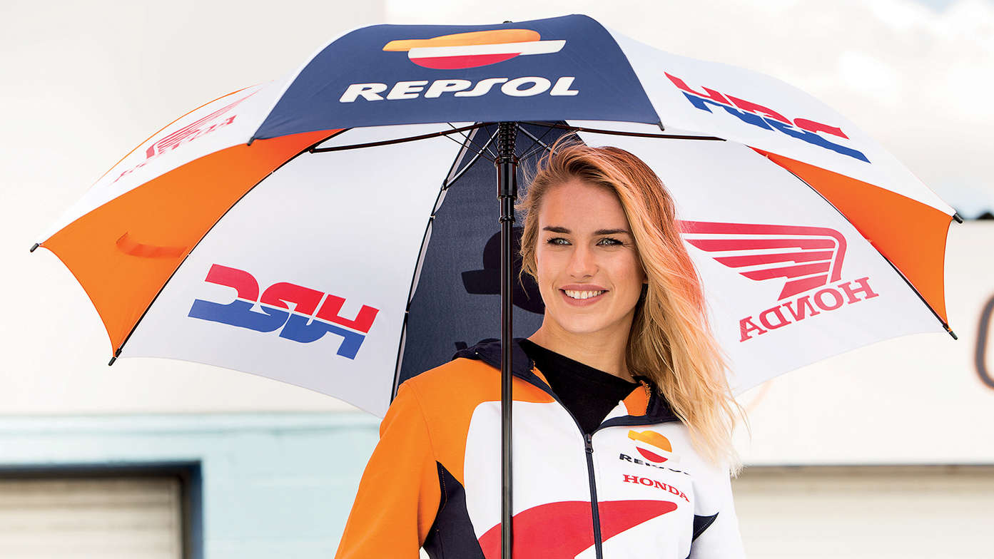 Woman smiling while holding Honda HRC umbrella.