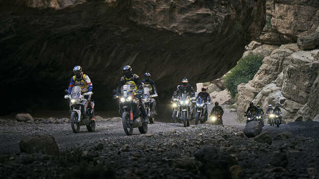 Africa Twin riders through mountain pass.