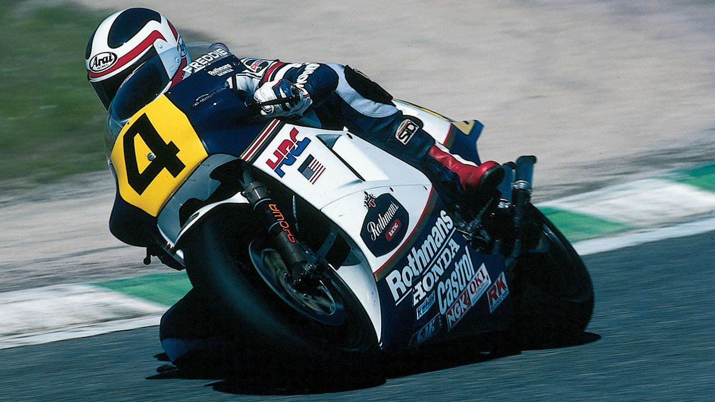 Front three-quarter facing Honda motorcycle with Freddie Spencer on MotoGP track.
