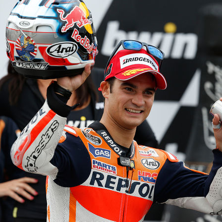 Rider on MotoGP podium with trophy.