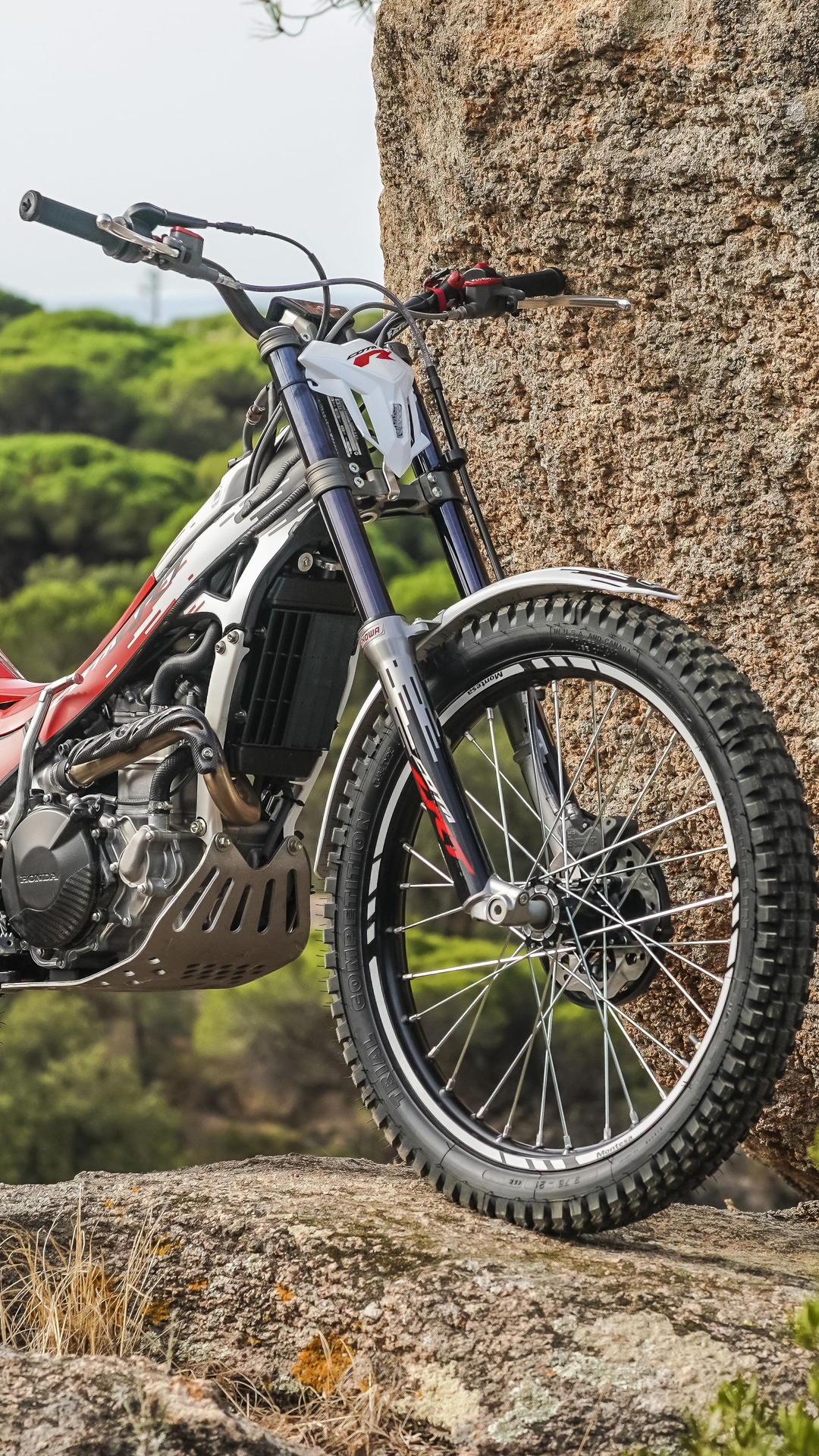 Montesa Cota 301RR trials bike standing on rocky terrain outdoors.