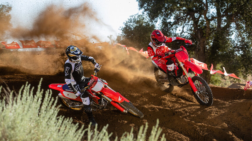 Two riders going over jumps on the Honda CRF450R.