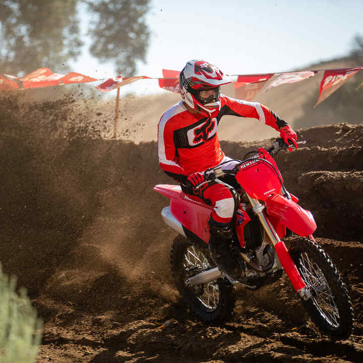 Honda CRF450R being ridden off road with mountains in the background.