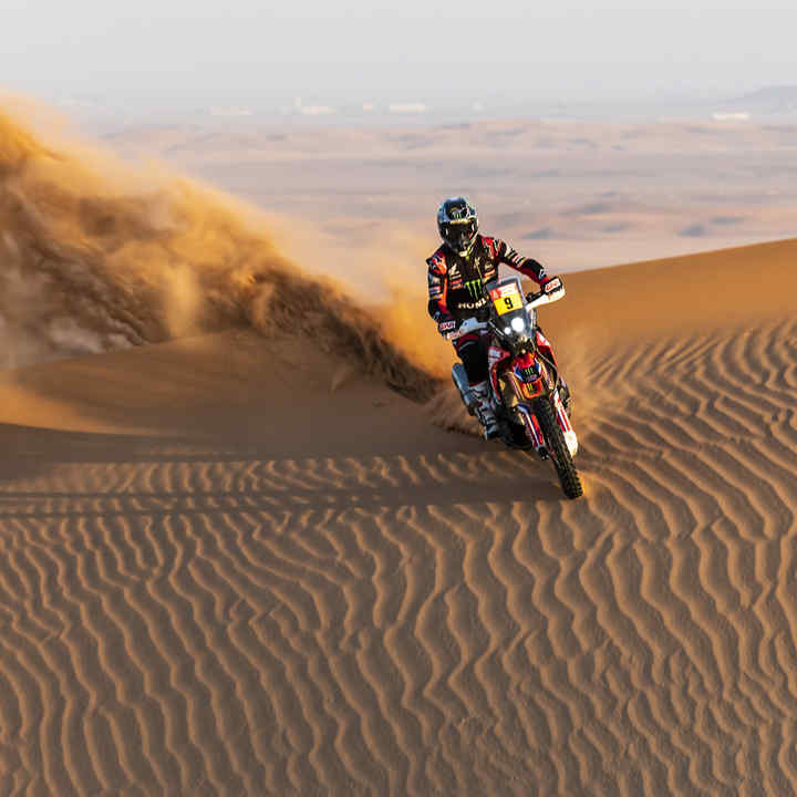 Honda Dakar rider in desert dunes. 