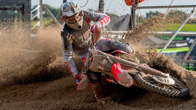 Front facing Honda Off Road motorcycle with rider, skidding through mud.