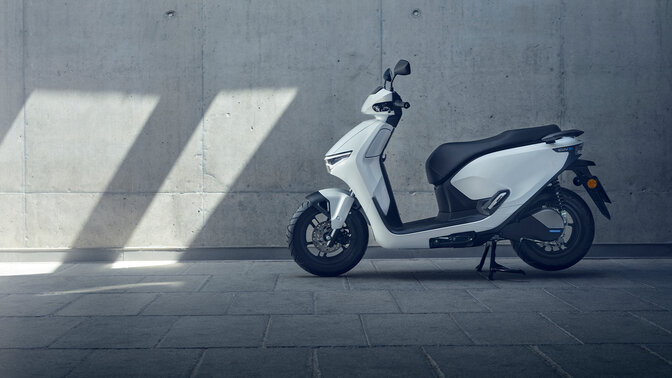 Honda CUV e motorcycle parked in a garage location.