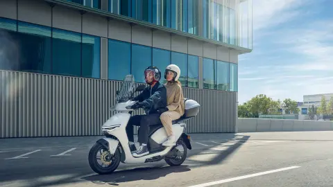 Models riding in the Honda CUV e motorcycle in a city location.