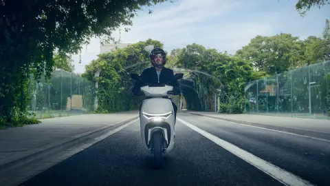 Front view of model riding a Honda CUV e motorcycle in a city location.
