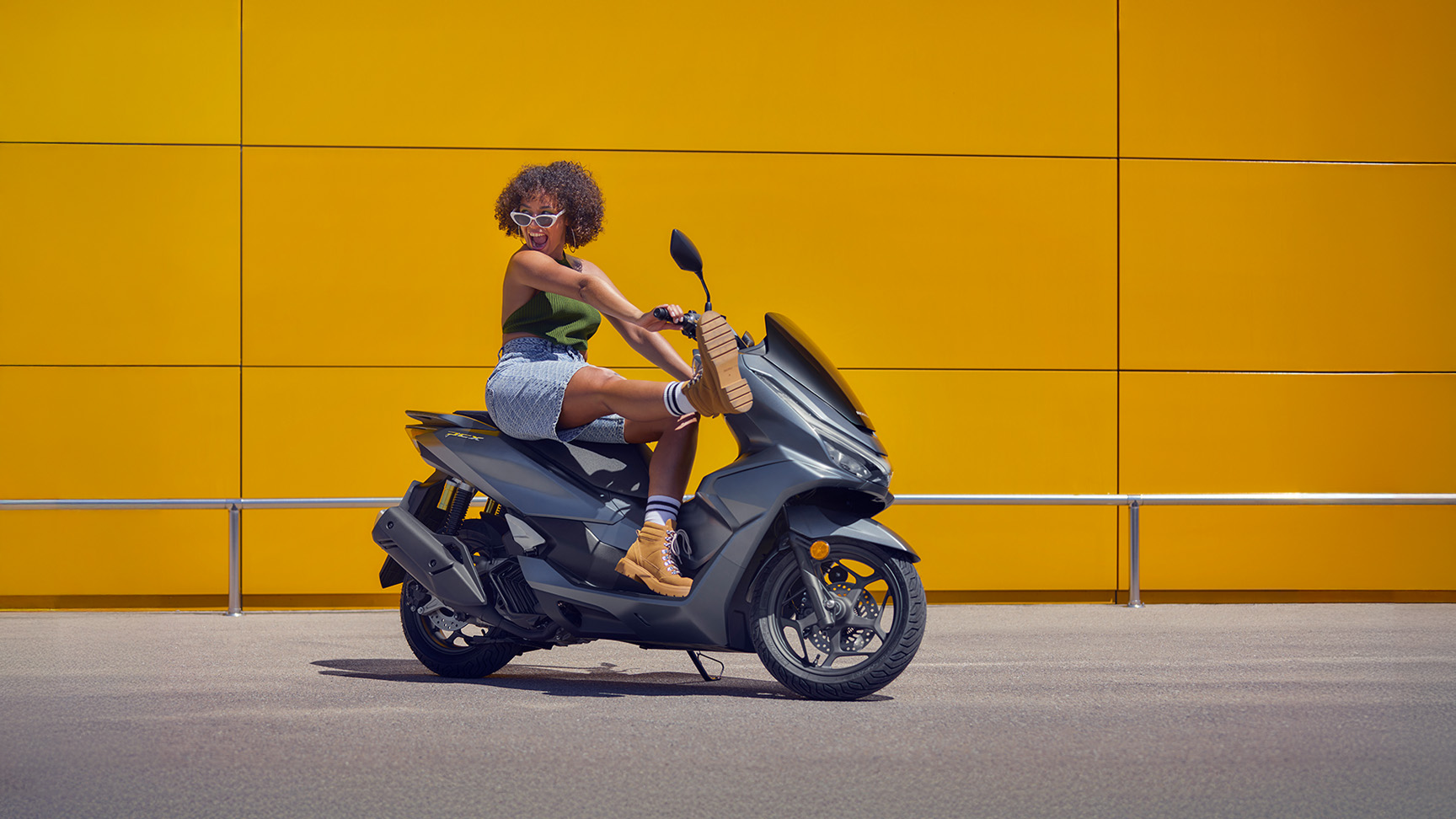 Model sitting on the PCX 125 motorcycle.