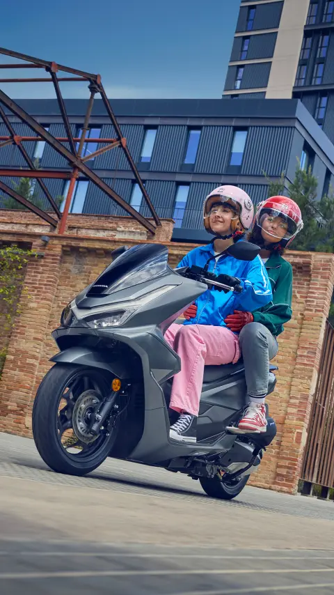 Models riding a PCX125 motorcycle in a city location.
