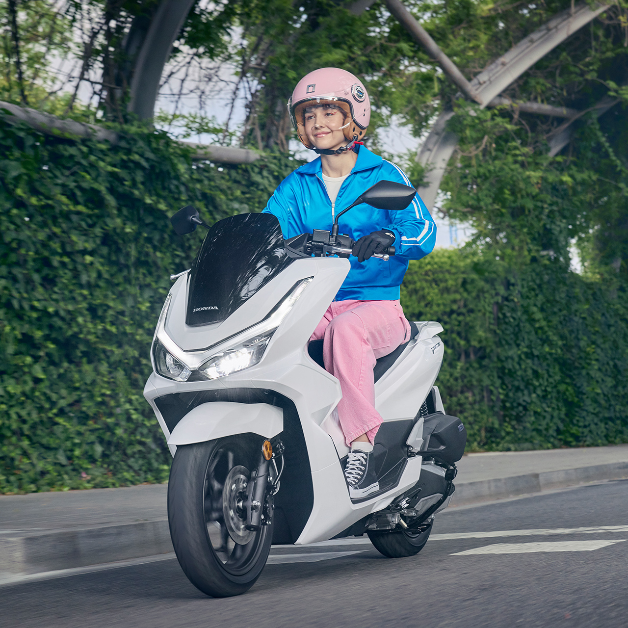 Model riding a PCX125 motorcycle in city location