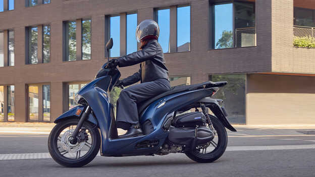 Rider on side facing Honda SH350 in city location.