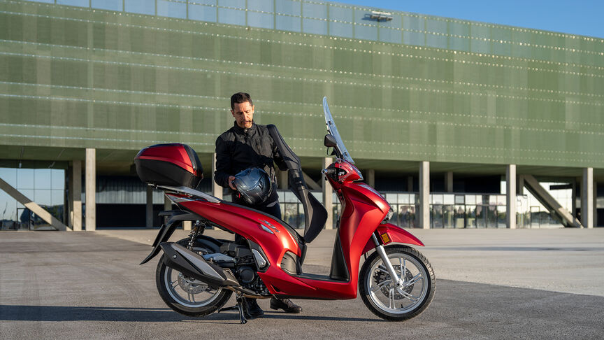 Honda SH350i, 3-quarter front right, with rider, on the road, red bike