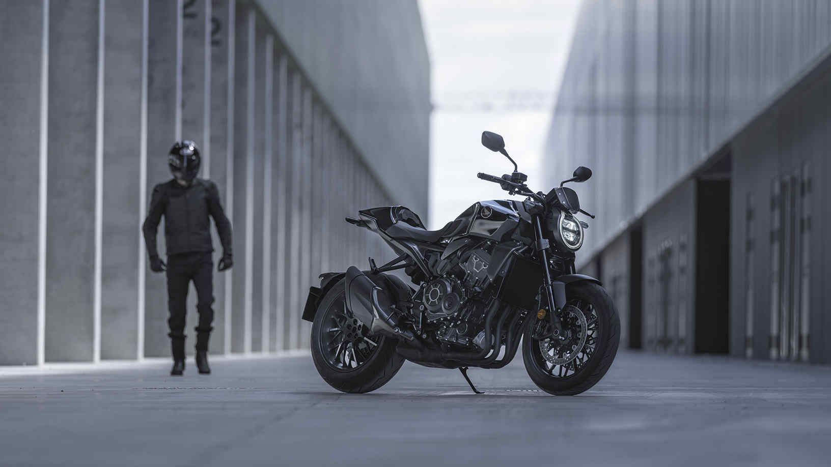 Honda CB1000R Black Edition - man standing next to the bike in the street between buildings