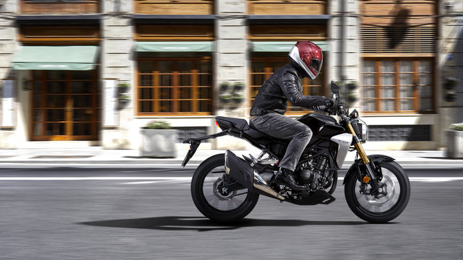 Side view action shot of Honda CB300R Neo Sports Café being ridden on the road.