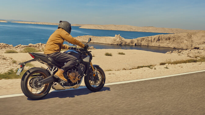 Honda CB650R riding away on coastal road