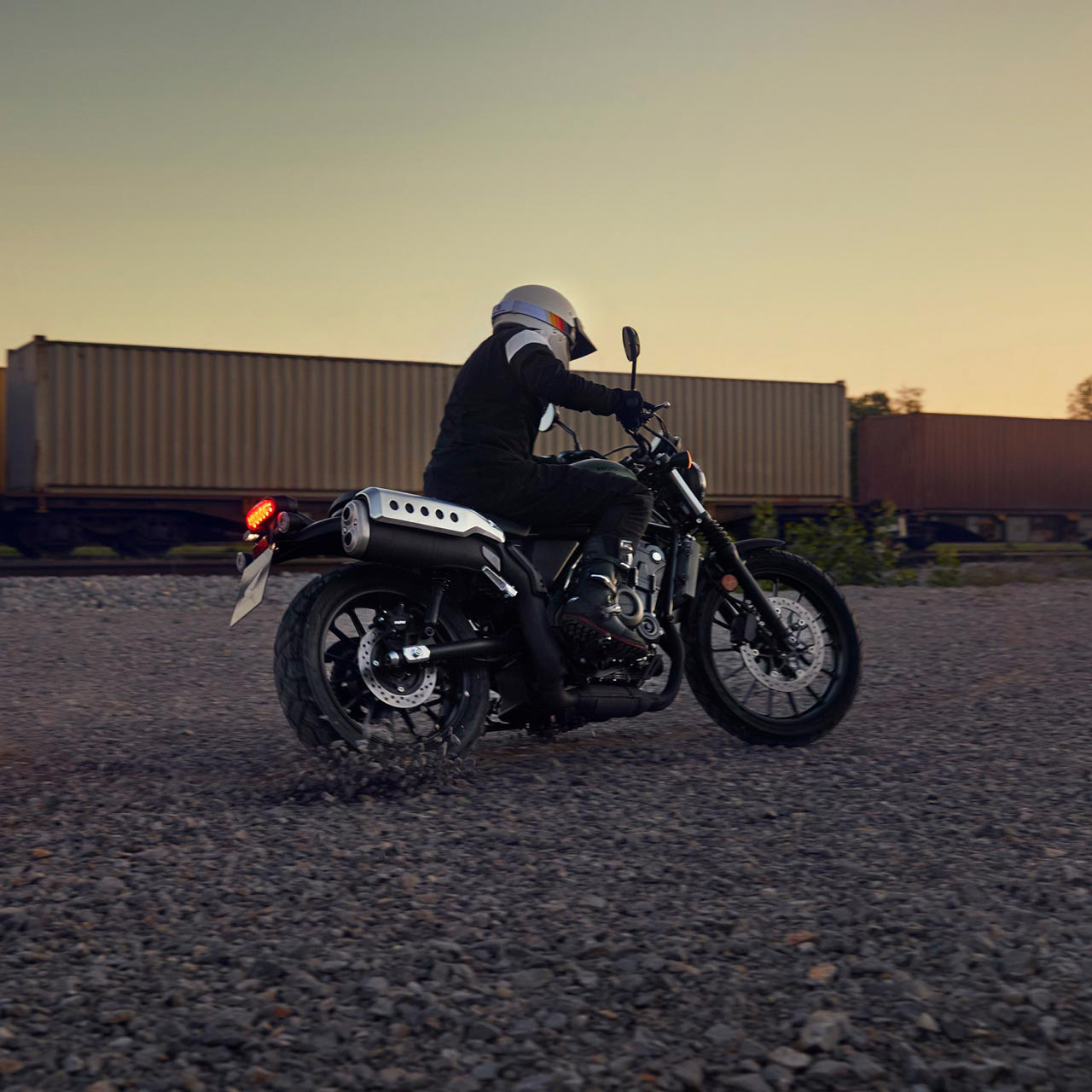 Model driving the Honda CL500 motorcycle in a warehouse location.