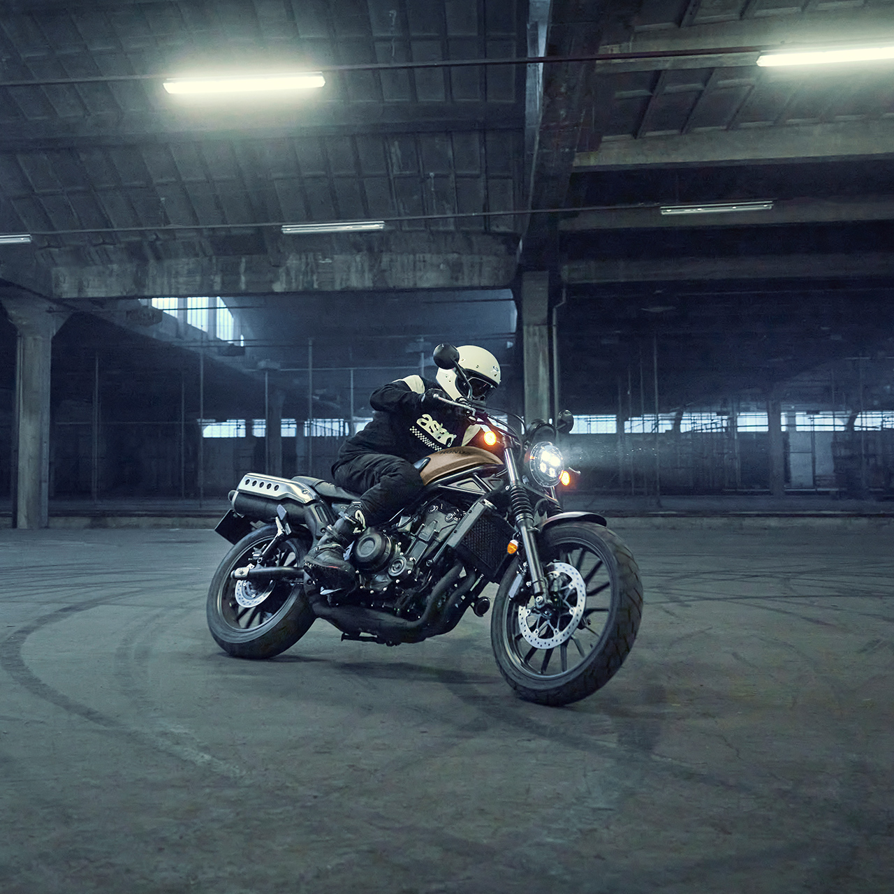 Model riding the Honda CL500 motorcycle in a parking location.