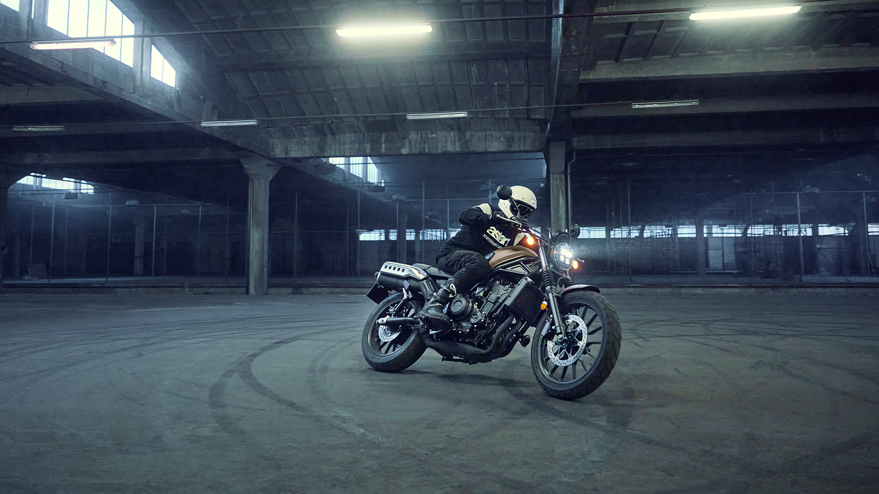 Model riding the Honda CL500 motorcycle in a parking location.