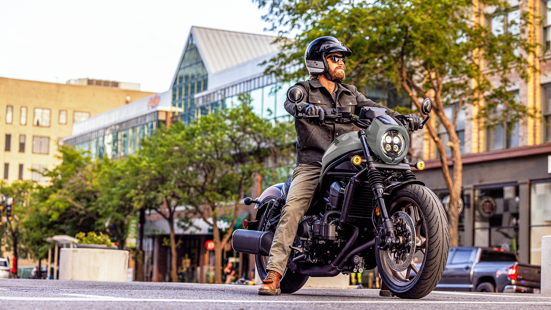 Model on a front facing Honda CMX1100 in city location.