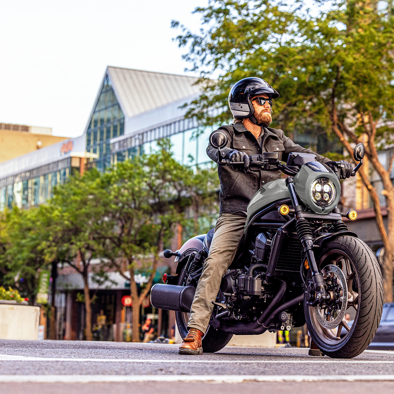 Model on a front facing Honda CMX1100 in city location.