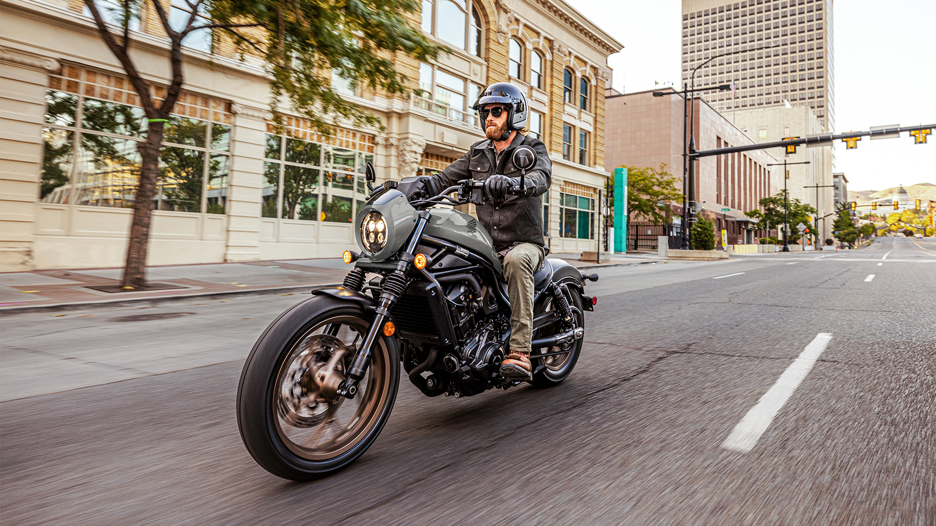 Model on front facing Honda CMX1100 in city location.