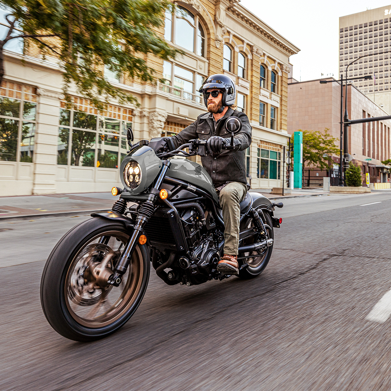 Model on front facing Honda CMX1100 in city location.