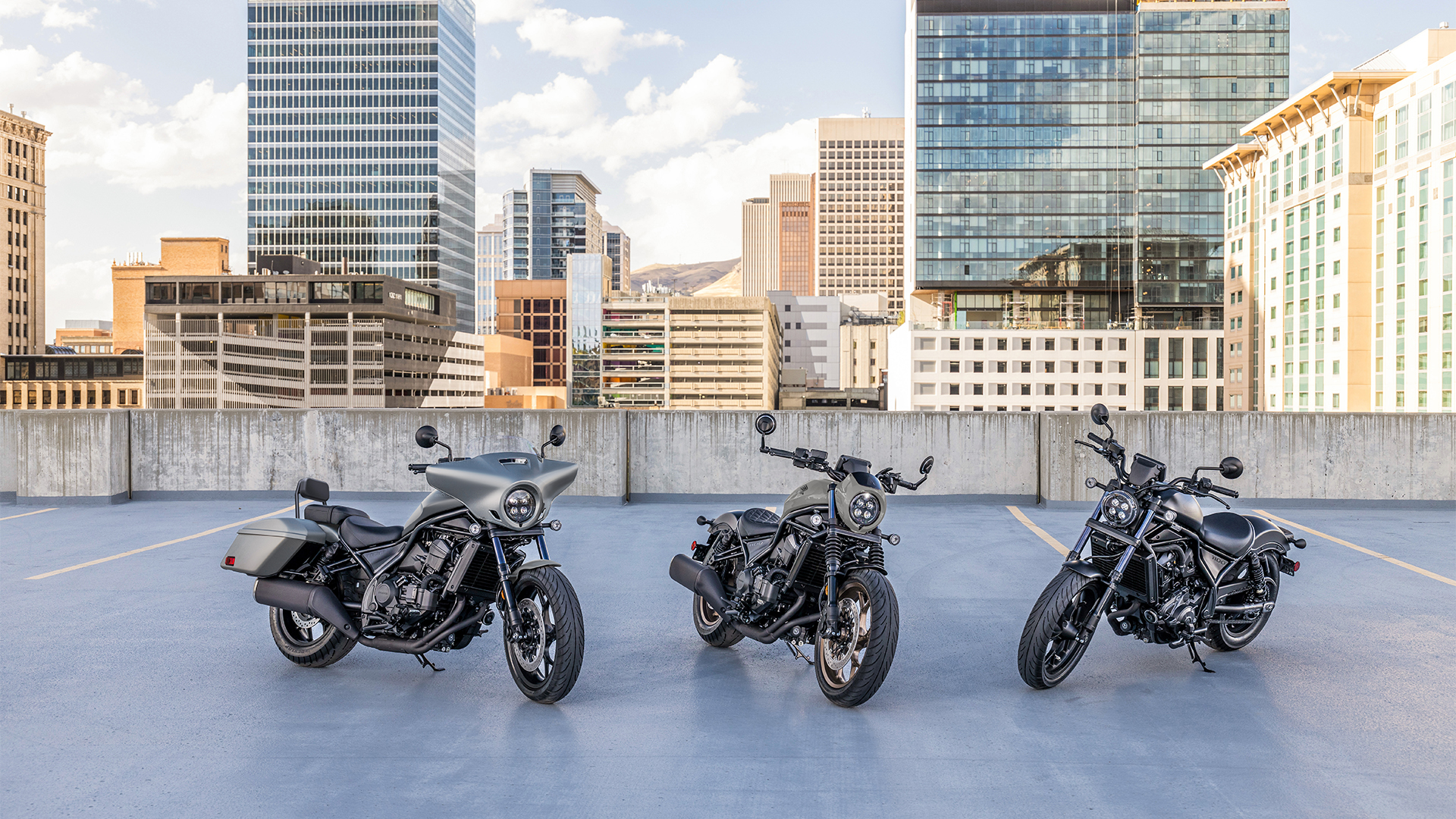 Three CMX1100 bikes outside, in front of modern buildings.