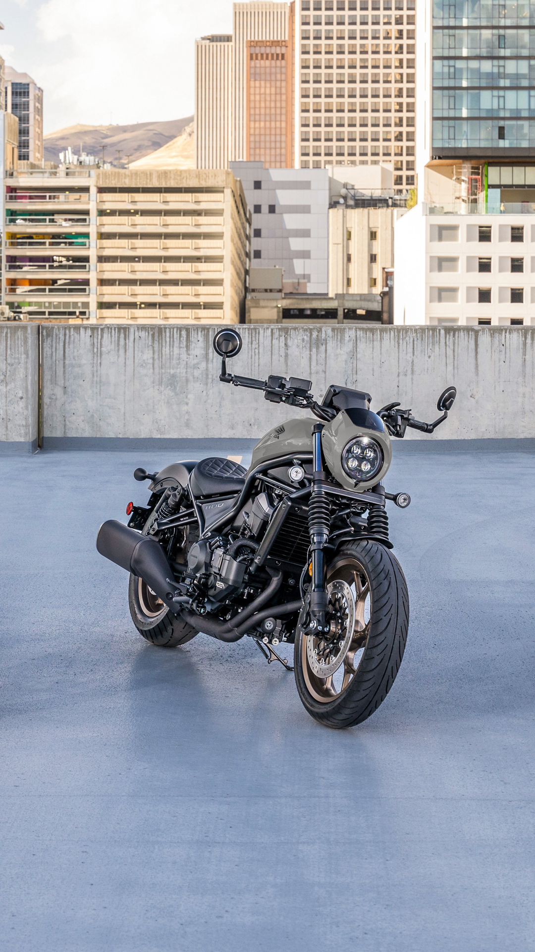 A CMX1100 bike outside, in front of a modern building.