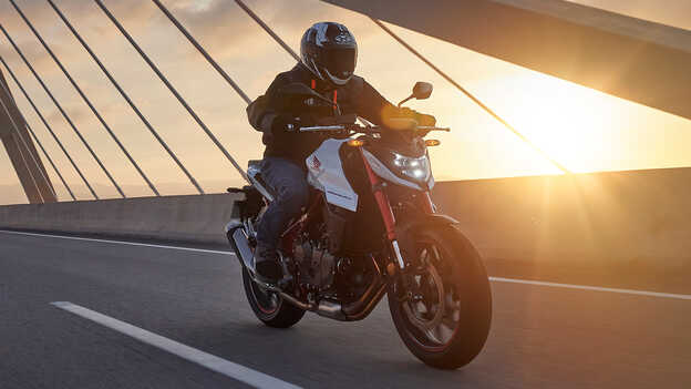 Honda CB750 being ridden over bridge.