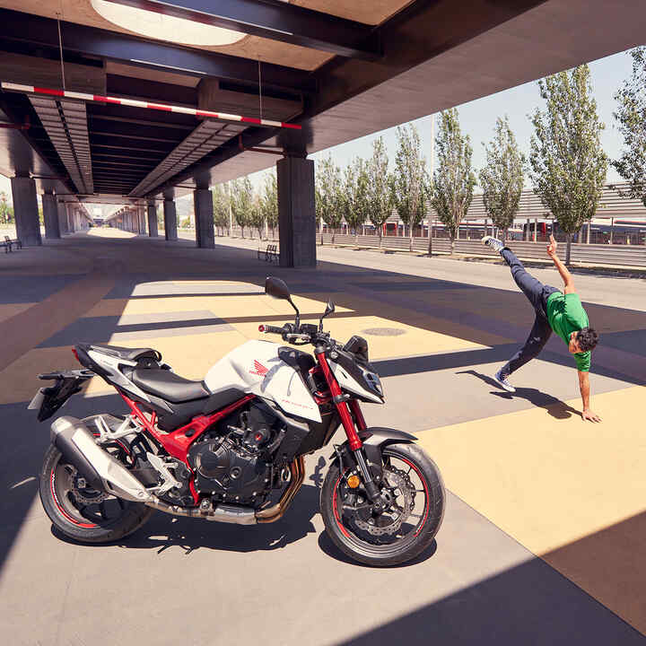 Honda CB750 Hornet under bridge with man breakdancing.