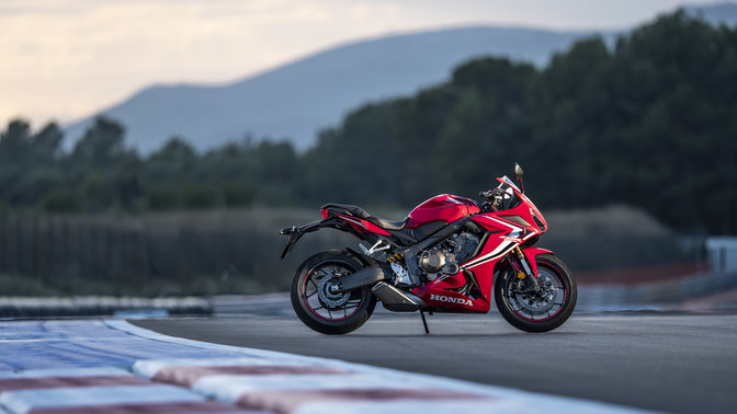 side view of red honda cbr 650r super sport motorcycle parked on a track